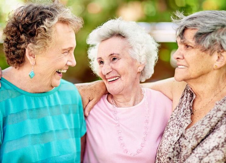 Three senior women walking and smiling outside