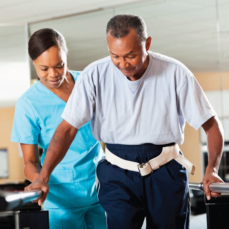 Senior man walking with help during a PT session