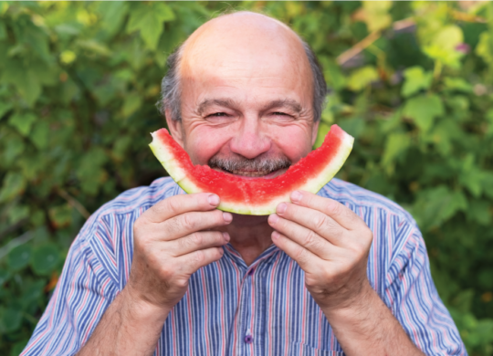 Man holding eaten watermelon rind as a smile face