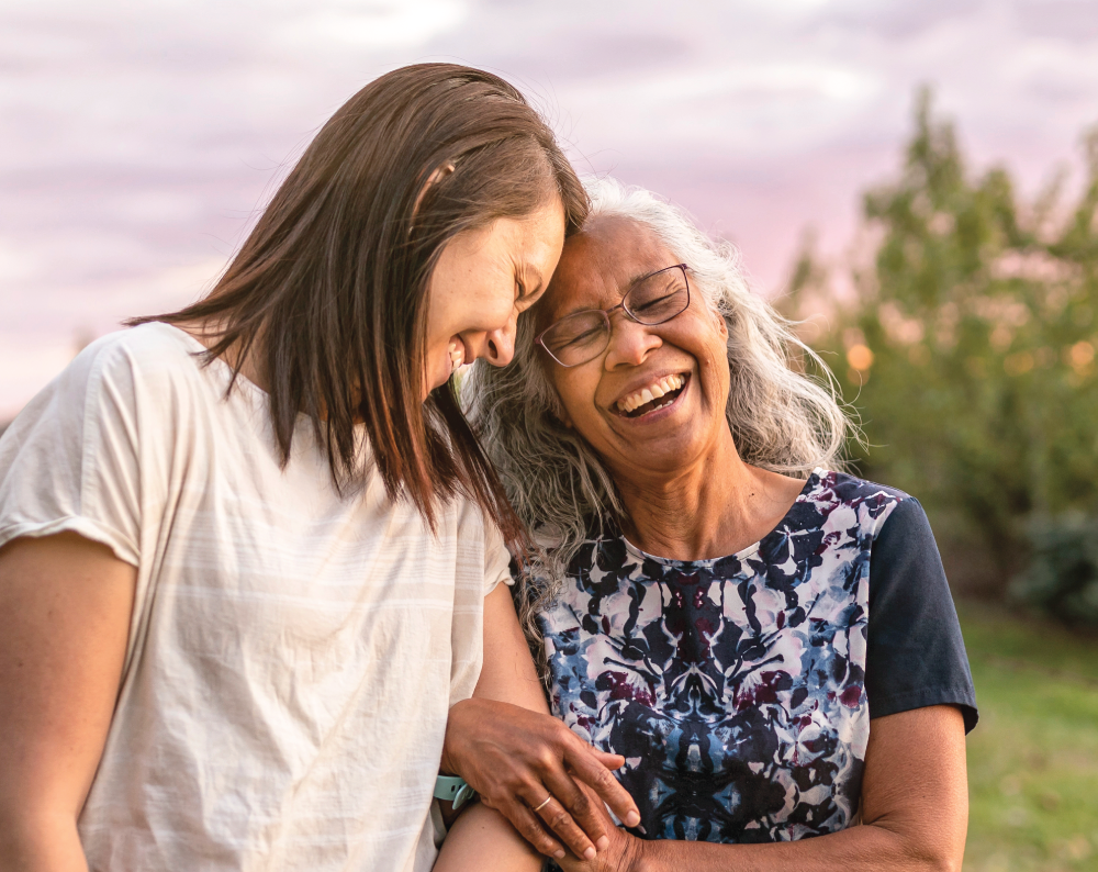 Staff member walking with a female resident outside smiling.