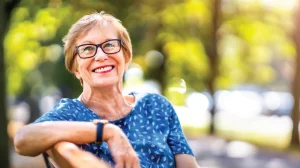 Senior woman in assisted living enjoying sitting on an outside bench